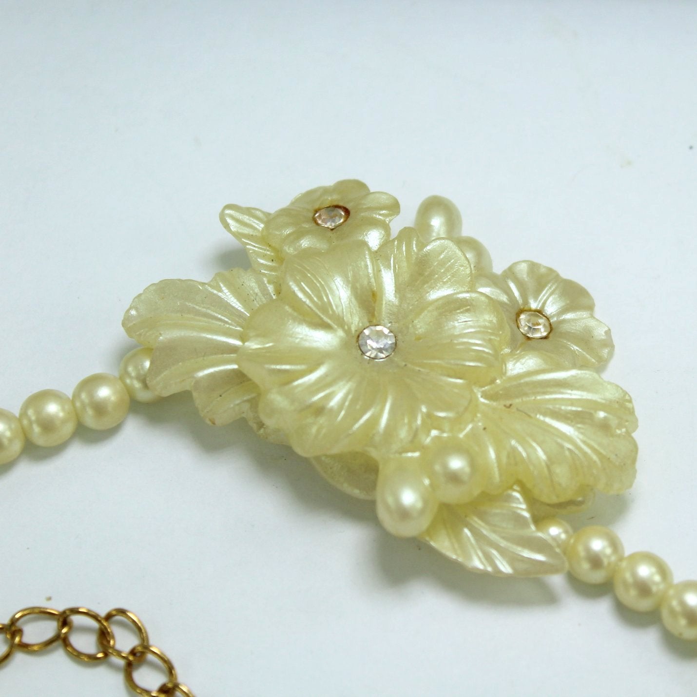 Vintage Necklace Molded Floral Bouquet Pearlized Ivory Rhinestone Centers closseup of focal