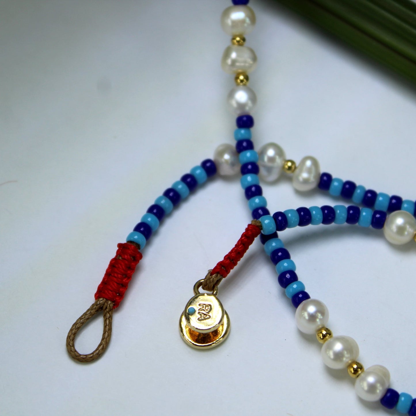 Roxanne Assoulin Necklace Blue Beads Pearls Classic Button Fastener Logo closeup and logo RA