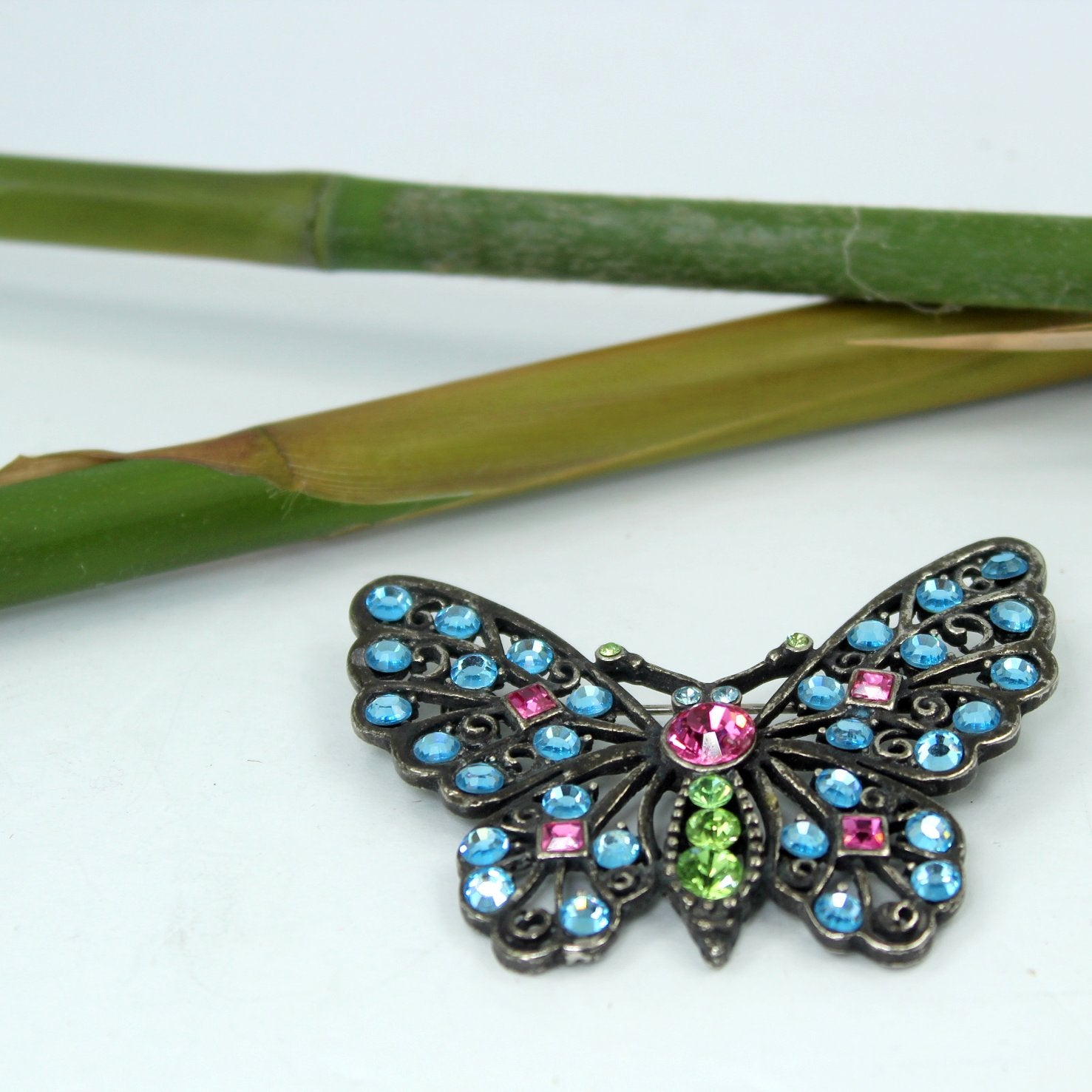Brilliant Crystal Butterfly Pin Pewter Finish Blues Green Bright Pink Sparkling table view of pin